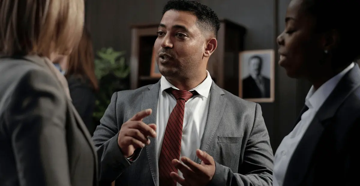 A DUI attorney in a gray suit and red tie speaking with two colleagues during a legal consultation