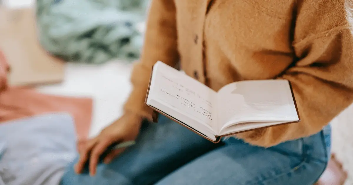 Person in a cozy sweater holding an open notebook and taking notes to prepare for a DUI court appearance