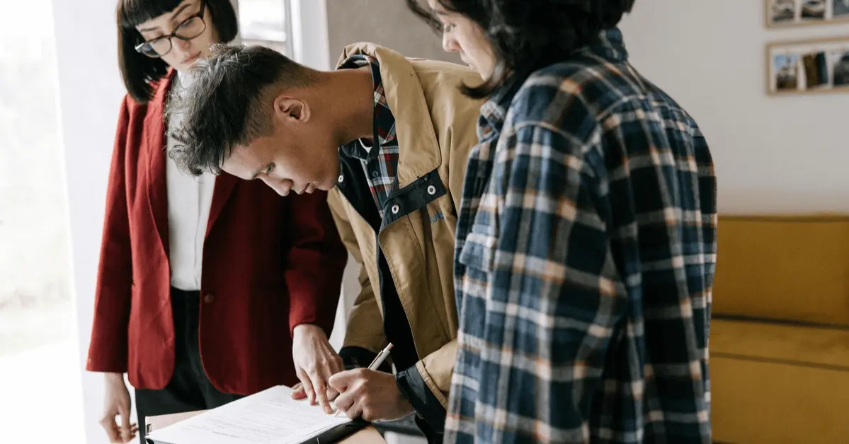 A man signing a legal document with two individuals observing, symbolizing the legal process after a DUI arrest.