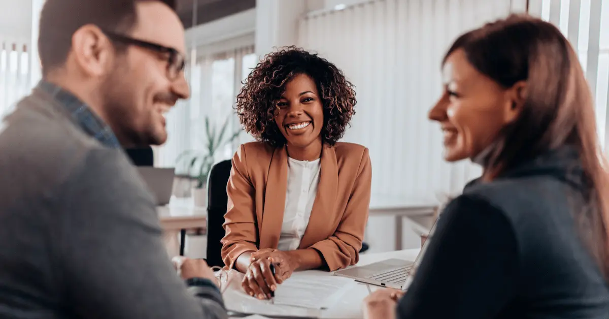 Smiling professional woman meeting with a couple across a desk, discussing the DUI court process in an office setting