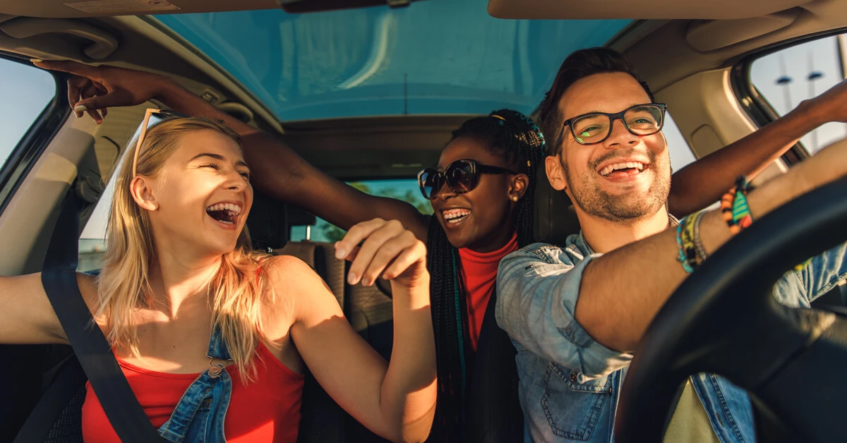 Three friends laughing and enjoying a road trip together