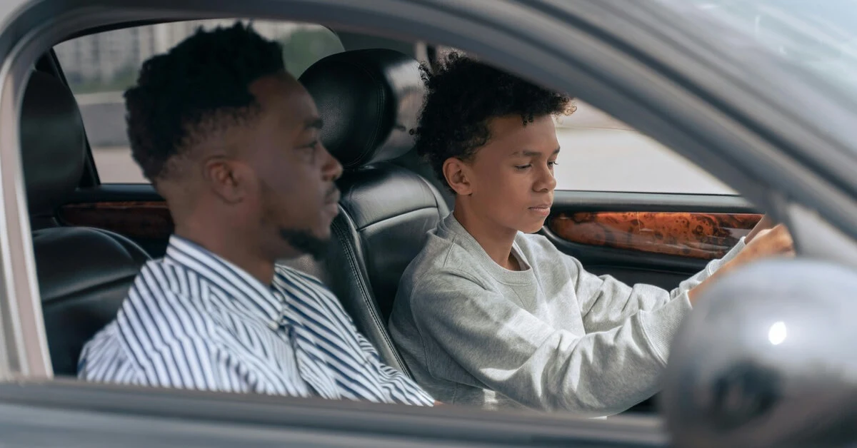 Teen driver focusing on the road with an adult supervising in the passenger seat