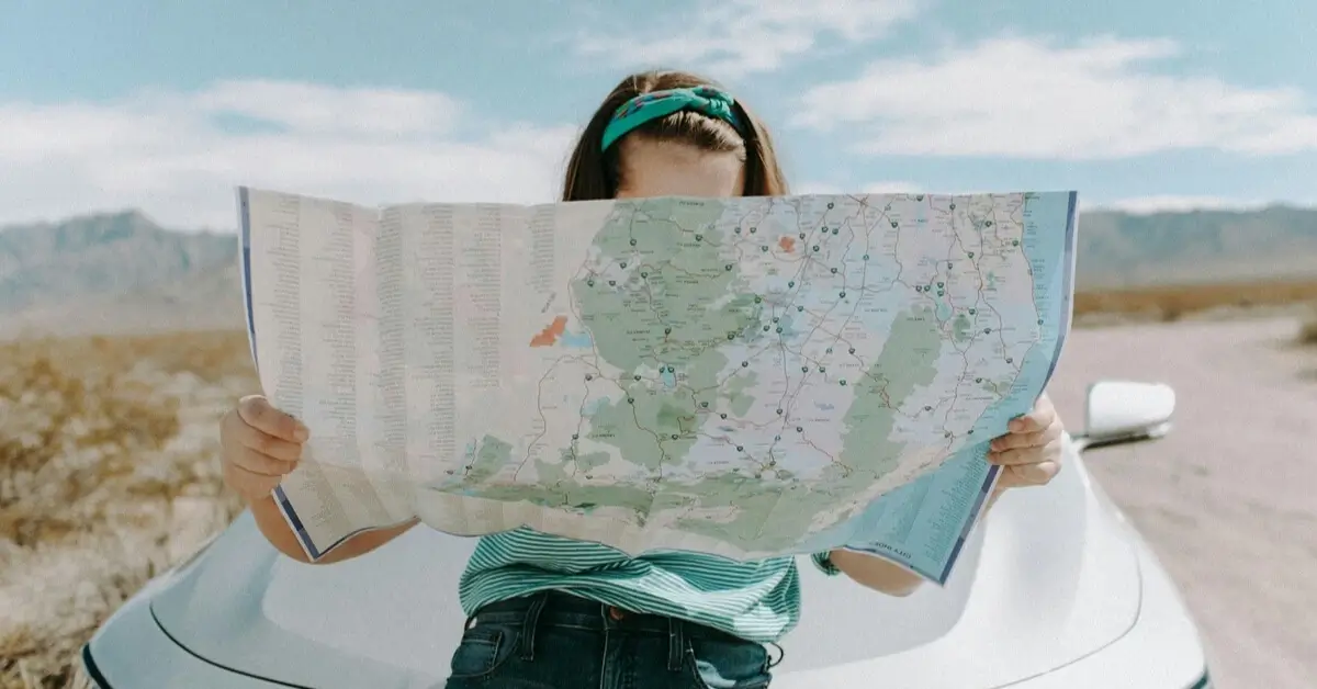 Woman standing in front of a car holding a large road map in Texas