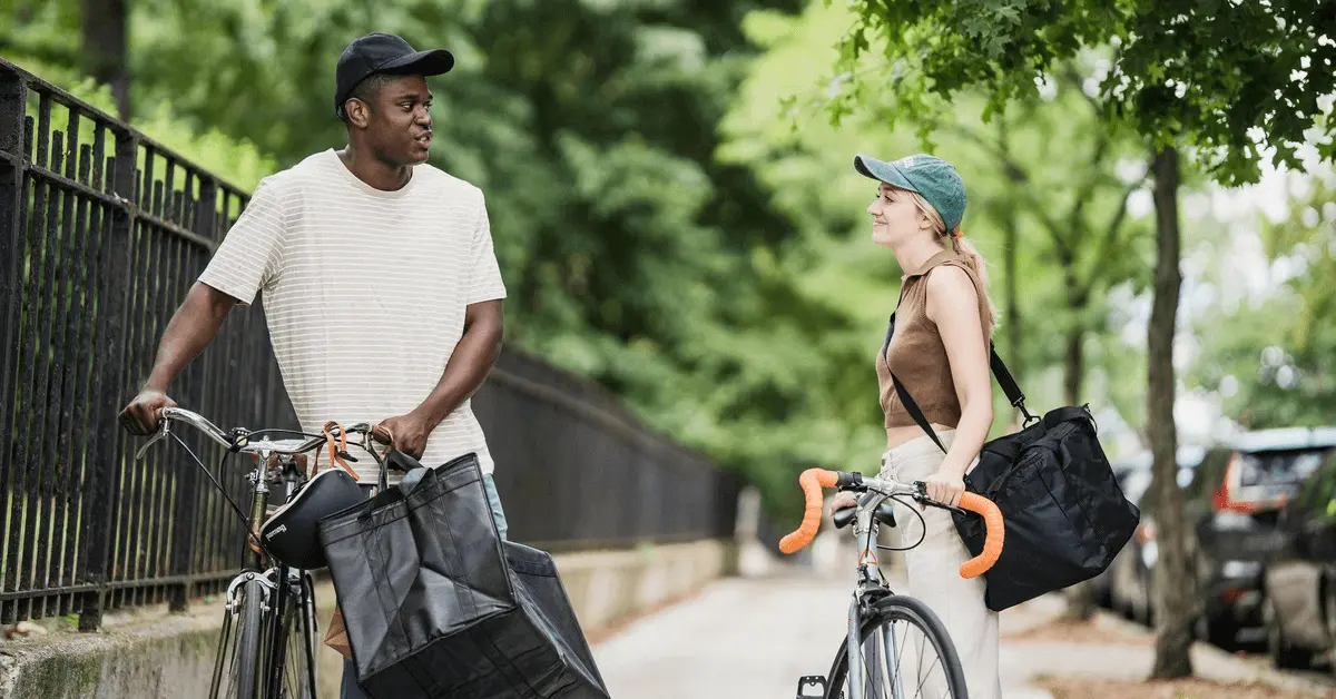 Two cyclists chatting by their bikes on a tree-lined street