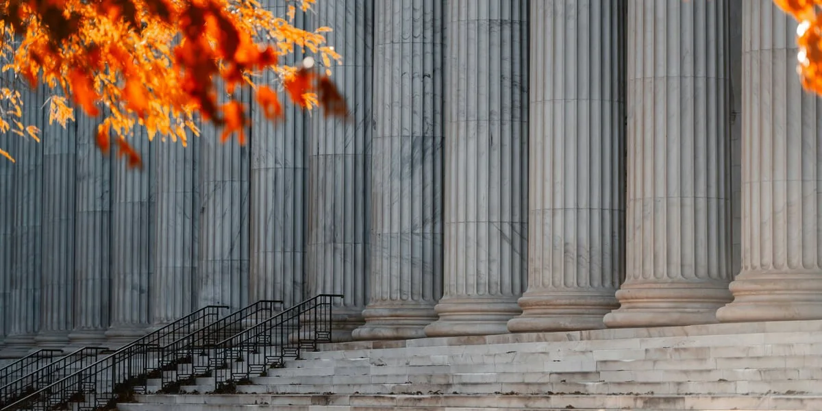 Marble courthouse steps with large columns framed by autumn leaves